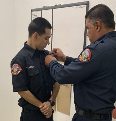 Glenn Lindsey, left, has his badge pinned on his shirt on his first day of work by Fire Apparatus Engineer Jacob Briones at the Soboba Fire Department on Jan. 31 Glenn Lindsey, left, has his badge pinned on his shirt on his first day of work by Fire Apparatus Engineer Jacob Briones at the Soboba Fire Department on Jan. 31