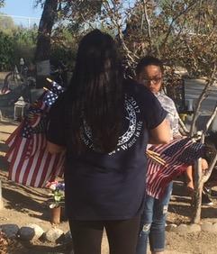 Activities Director and Soboba Youth Council Coordinator Jennifer DeVore-Garcia hands American flags to her daughter, Ashlynn Russell, to place on the graves Activities Director and Soboba Youth Council Coordinator Jennifer DeVore-Garcia hands American flags to her daughter, Ashlynn Russell, to place on the graves
