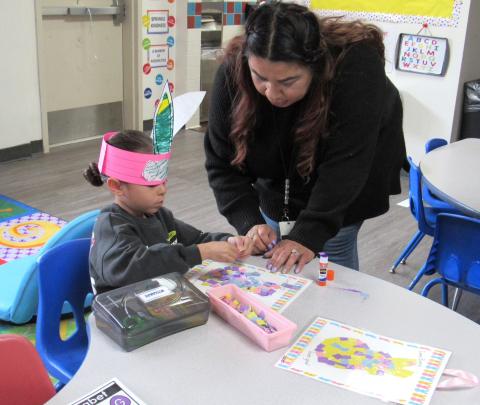 Pre-K teacher Ana Garcia helps Nokaamay Mathews-Garcia complete his mosaic bunny activity during Spring party day Pre-K teacher Ana Garcia helps Nokaamay Mathews-Garcia complete his mosaic bunny activity during Spring party day