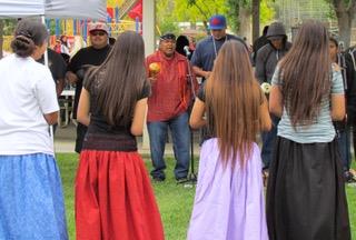 Kim Marcus, center, leads students and community members in bird songs as bird dancers join in during Noli Indian School’s Annual Fiesta on May 18