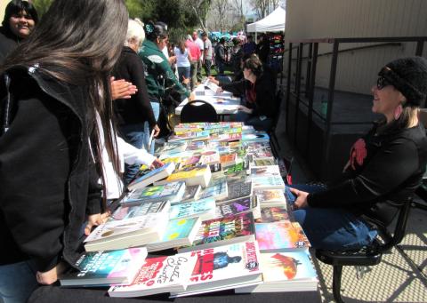 Noli reading teacher Jacquelin Phillips, right, encourages students and others to take a free book during the school’s annual gathering, April 4 Noli reading teacher Jacquelin Phillips, right, encourages students and others to take a free book during the school’s annual gathering, April 4