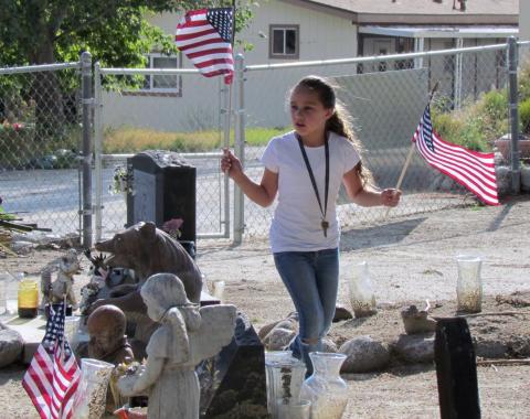 Noyáaykit Silvas, 7, helps her dad and others place flags at the gravesites of veterans buried at Soboba Cemetery in preparation of a Memorial Day ceremony Noyáaykit Silvas, 7, helps her dad and others place flags at the gravesites of veterans buried at Soboba Cemetery in preparation of a Memorial Day ceremony