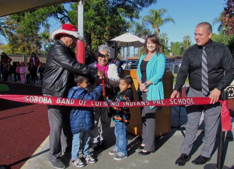Kindergartners Mac Pineda and Muukumikat Gonzalez help cut the ribbon for the new Soboba Tribal Preschool playground, dedicated on Dec. 9. Adults helping, from left, Tribal Council Chairman Scott Cozart, Tribal Elder Marian Chacon, Preschool Director Dianne King and Tribal Administrator Michael Castello Kindergartners Mac Pineda and Muukumikat Gonzalez help cut the ribbon for the new Soboba Tribal Preschool playground, dedicated on Dec. 9. Adults helping, from left, Tribal Council Chairman Scott Cozart, Tribal Elder Marian Chacon, Preschool Director Dianne King and Tribal Administrator Michael Castello